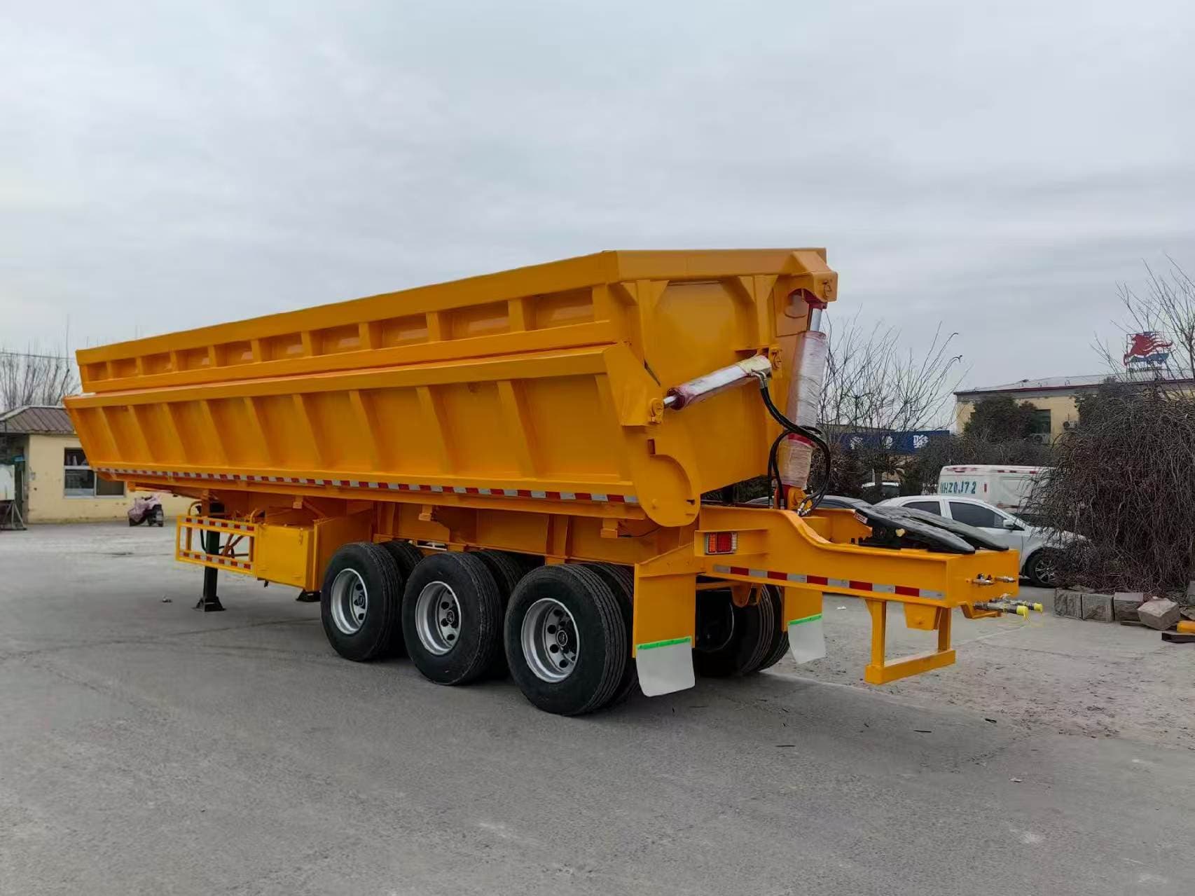 Yellow side-tipping semi-trailer photographed with a tractor at the supplier yard